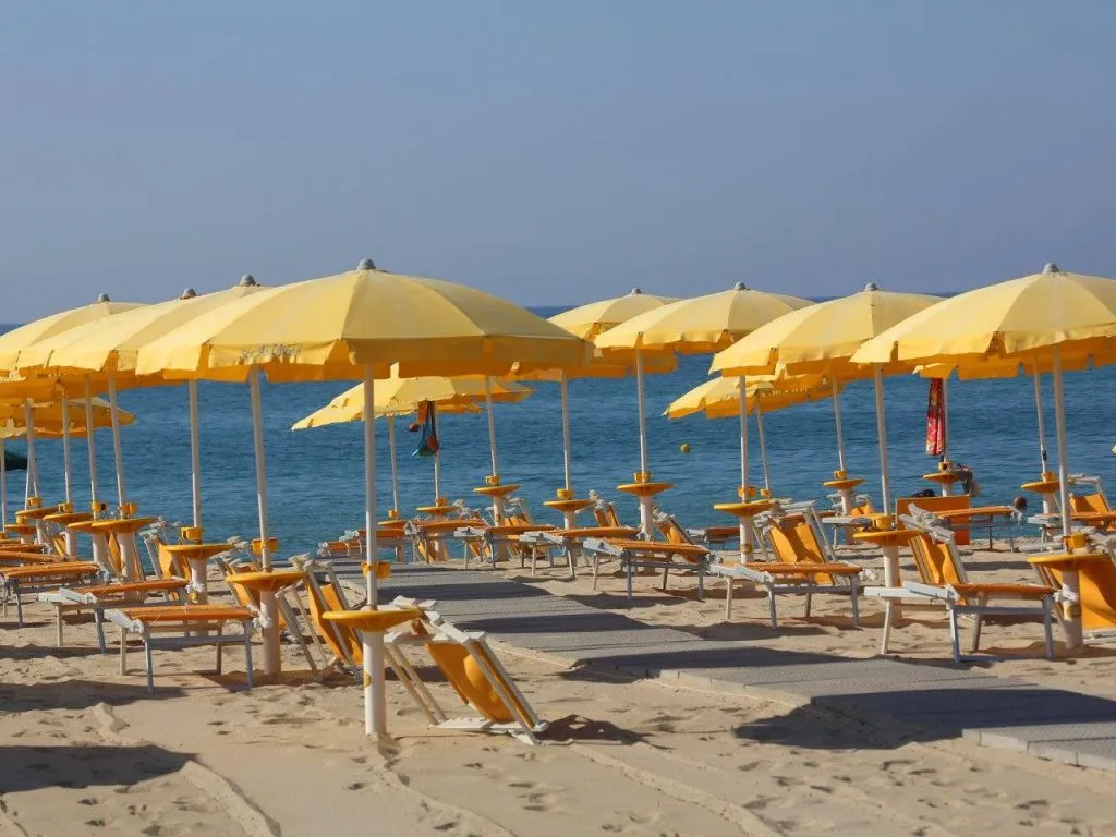 File di ombrelloni gialli e lettini sulla spiaggia con vista sul mare