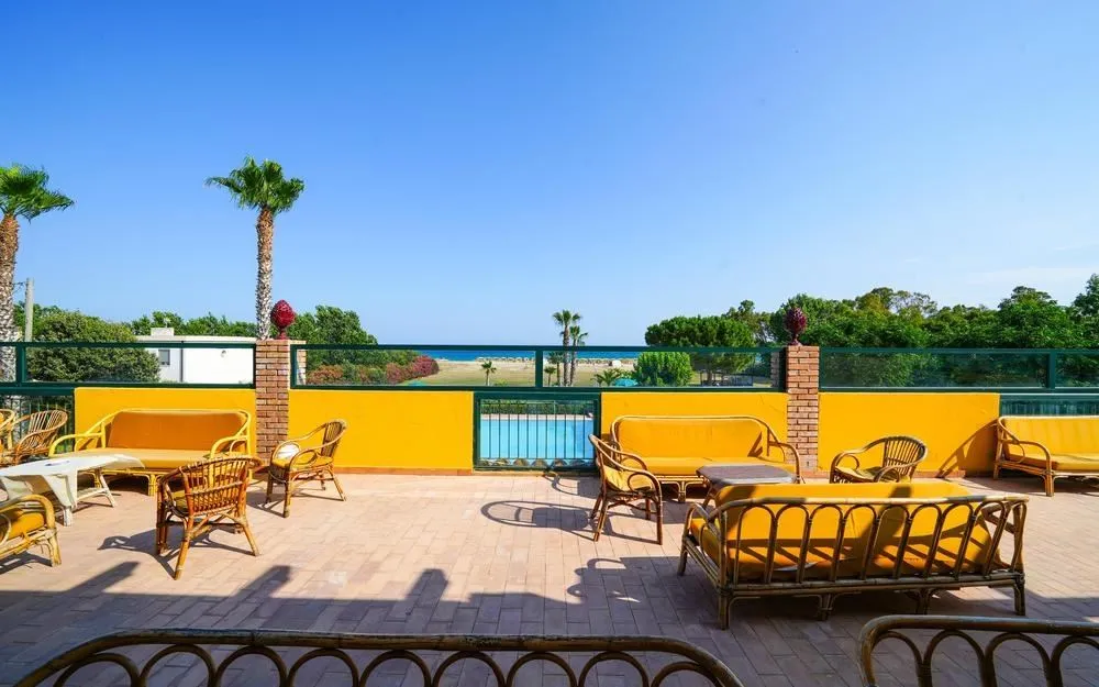 Terrazza con divani e poltrone in vimini gialli e vista sul mare