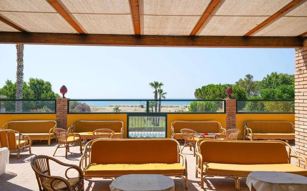 Terrazza coperta da pergolato con divani gialli in vimini e vista panoramica sul mare