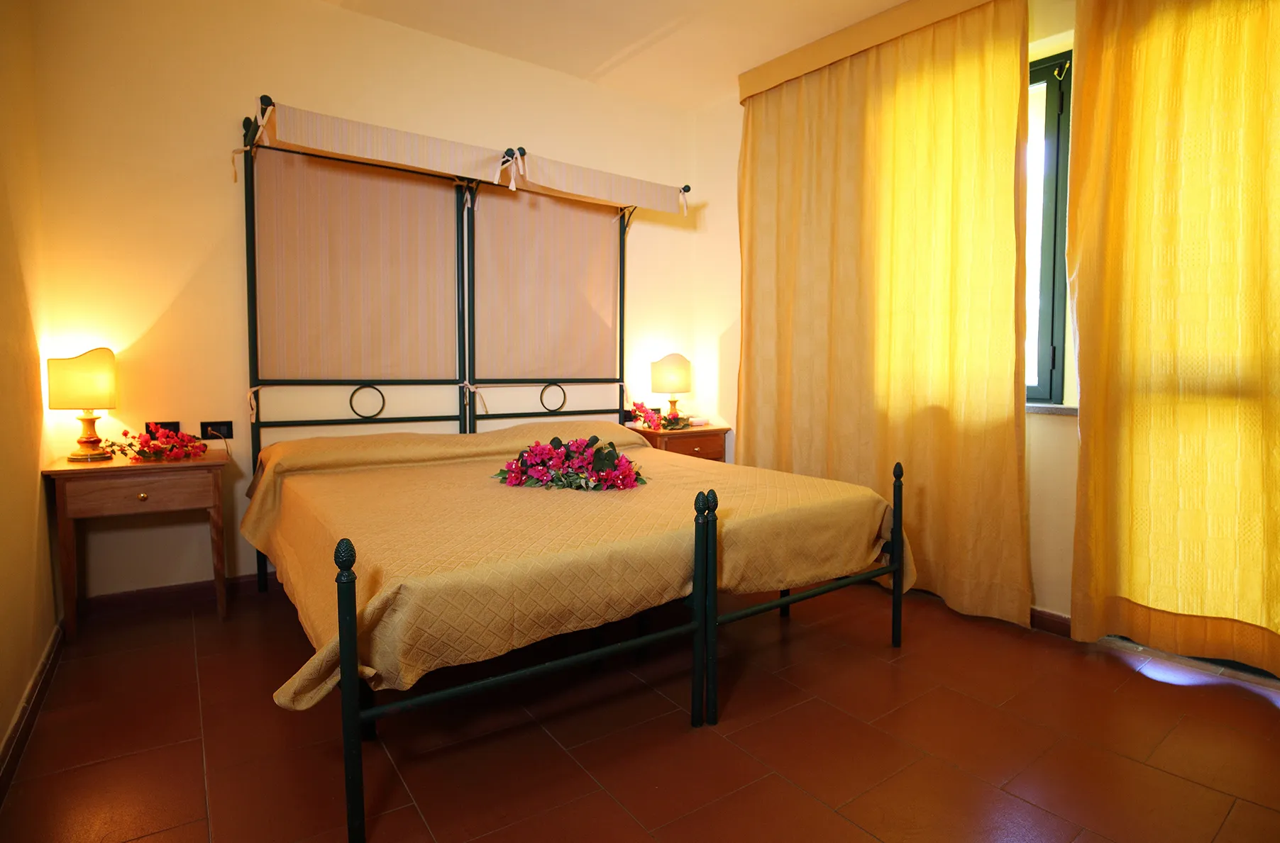 Camera matrimoniale con letto in ferro battuto, baldacchino e tende gialle