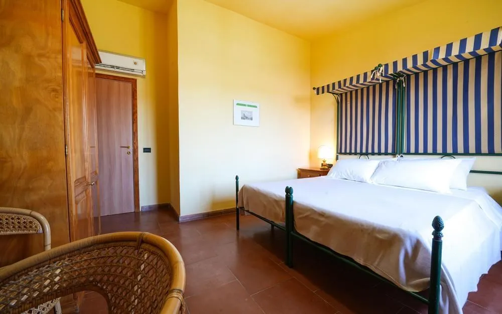 Camera matrimoniale con letto a baldacchino a righe blu, aria condizionata e armadio in legno