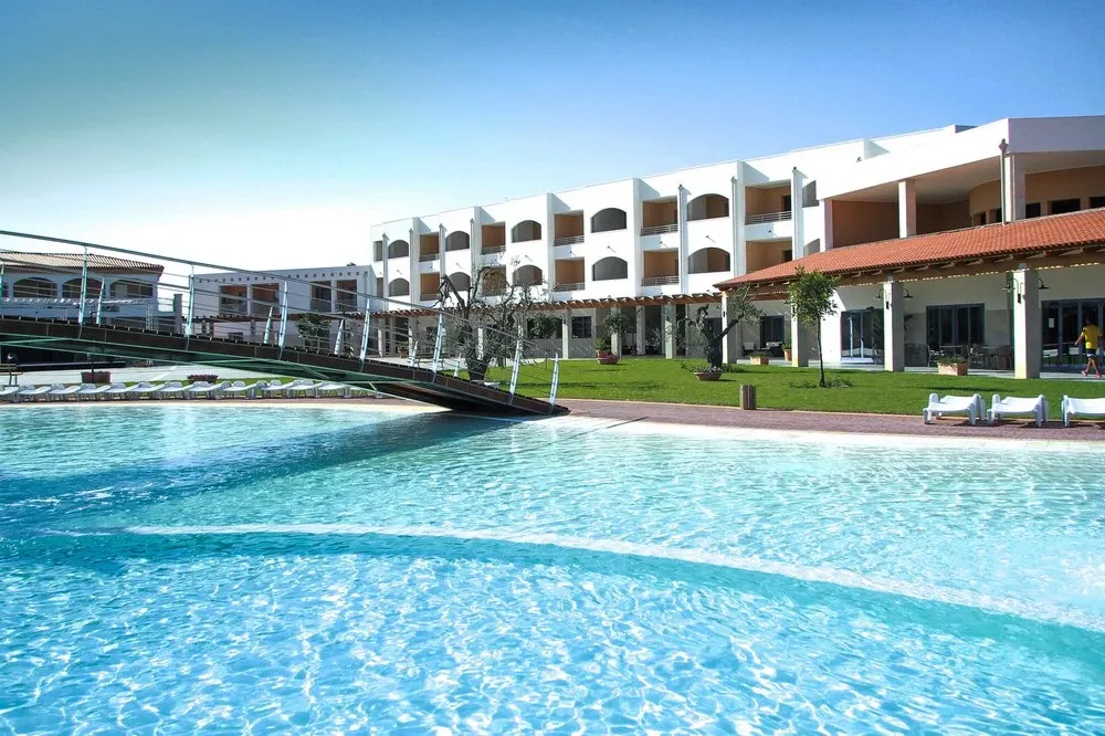Piscina con acqua cristallina e ponte pedonale davanti all'edificio del resort
