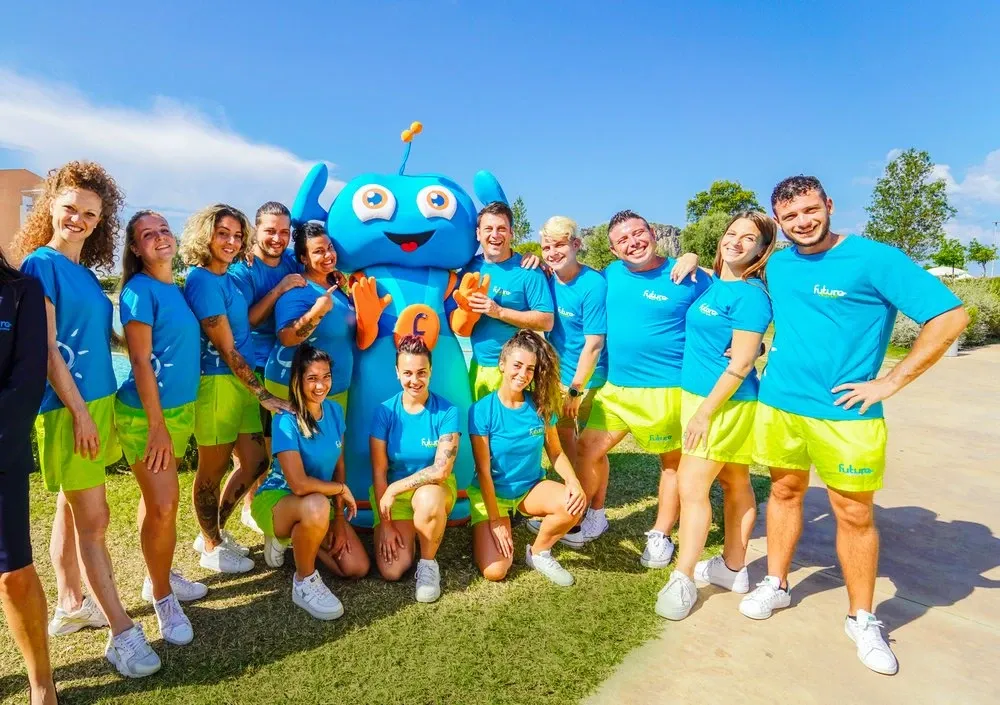 Team di animazione con mascotte del villaggio posa sorridente all'aperto