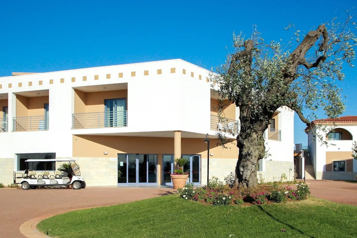 Facciata moderna dell'edificio del resort con ulivo secolare e voiturette