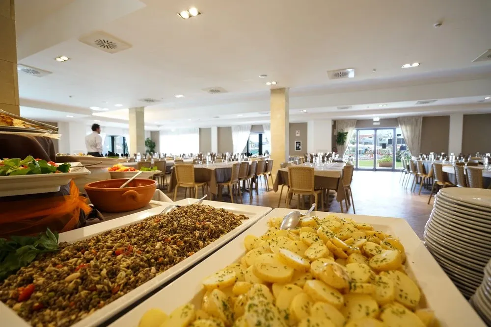 Buffet del ristorante con piatti caldi e sala da pranzo sullo sfondo