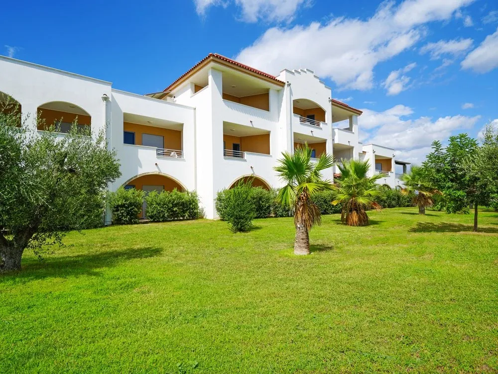 Edificio del resort con giardino verde, ulivi e palme