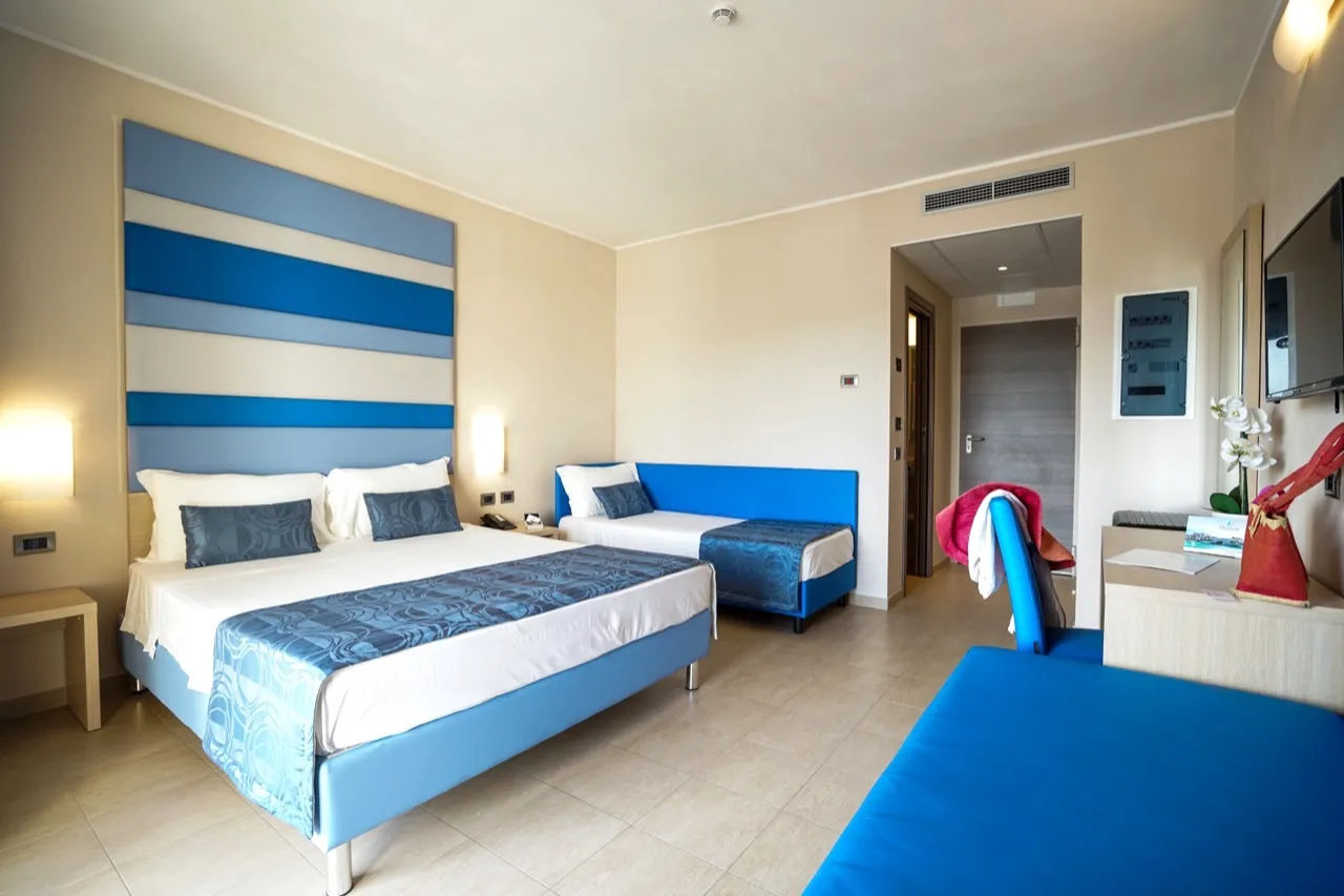 Camera doppia con letto matrimoniale, testiera a righe blu e TV