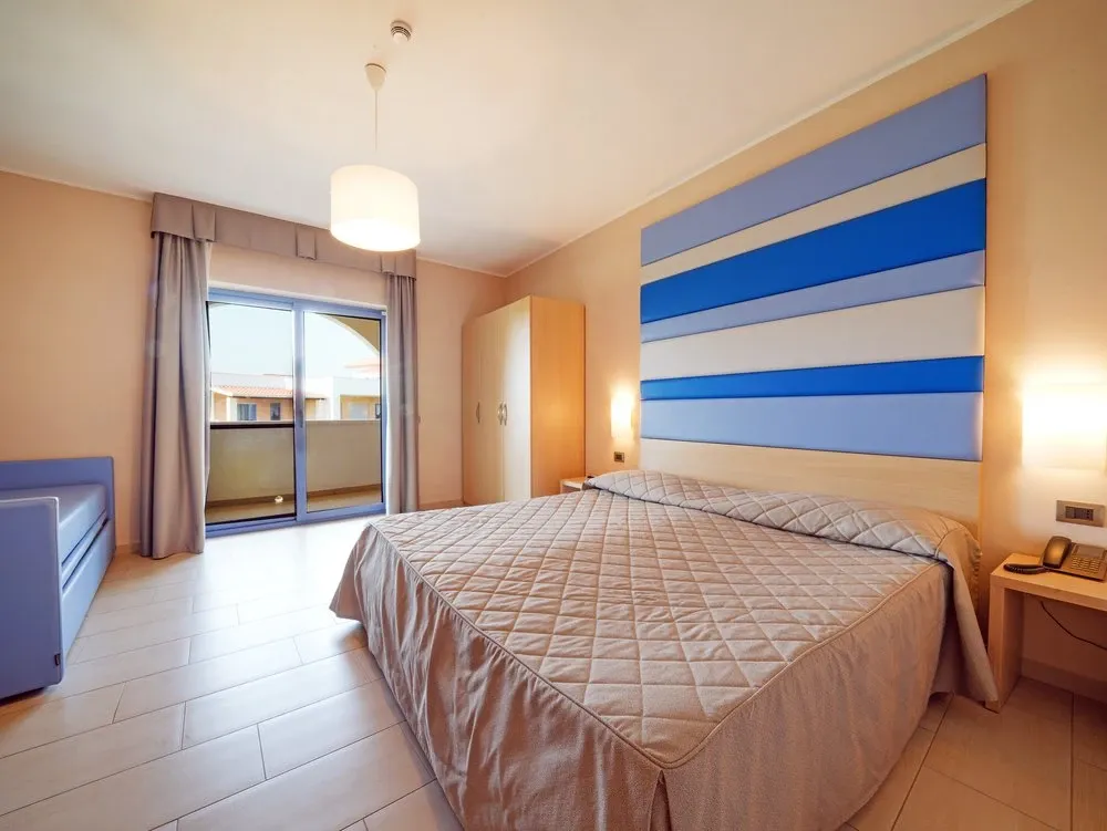 Camera da letto con letto matrimoniale, testiera a righe blu e balcone
