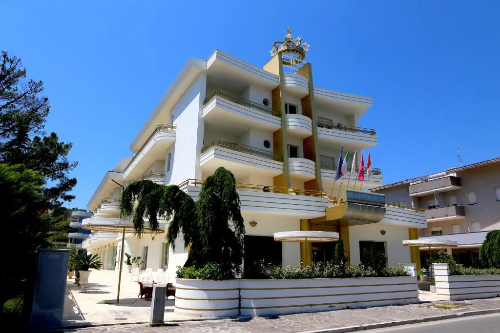 Vista laterale della facciata bianca dell'hotel con balconi e bandiere sotto cielo azzurro