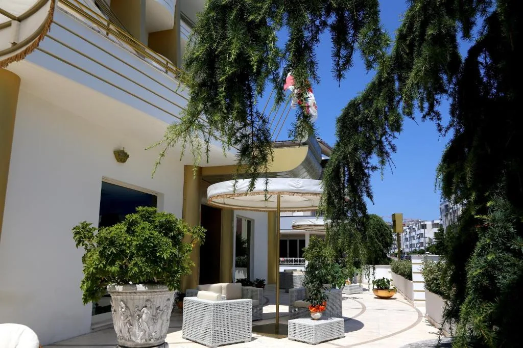 Terrazza esterna dell'hotel con divani in rattan bianco, ombrellone e piante