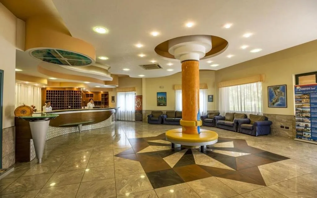 Hall dell'hotel con reception curva, colonna centrale arancione, divani e pavimento in marmo decorato