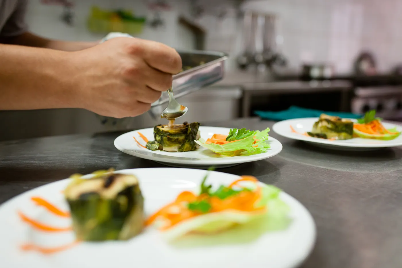 Chef che impiatta un piatto gourmet di verdure in cucina professionale