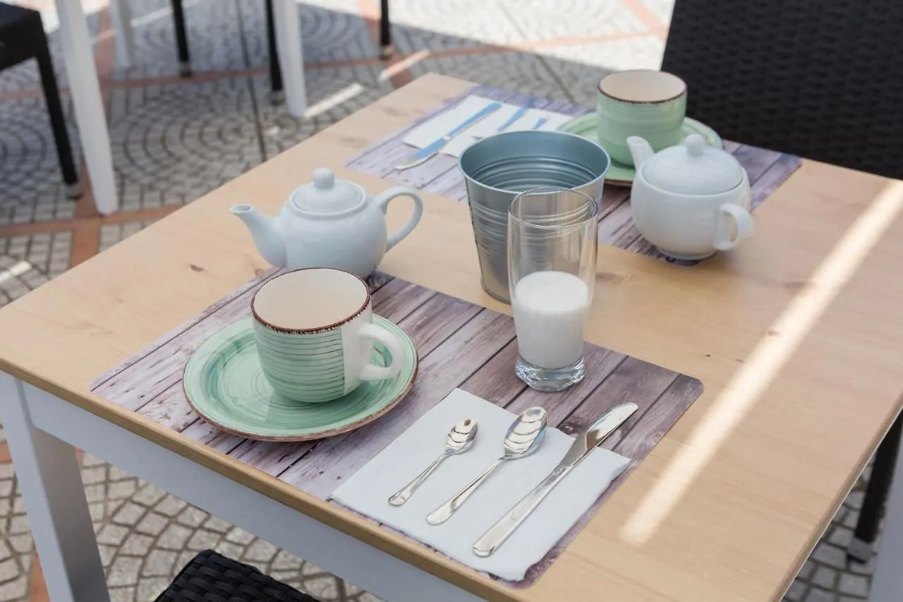Tavolo apparecchiato per la colazione con teiere, tazze in ceramica e bicchiere di latte