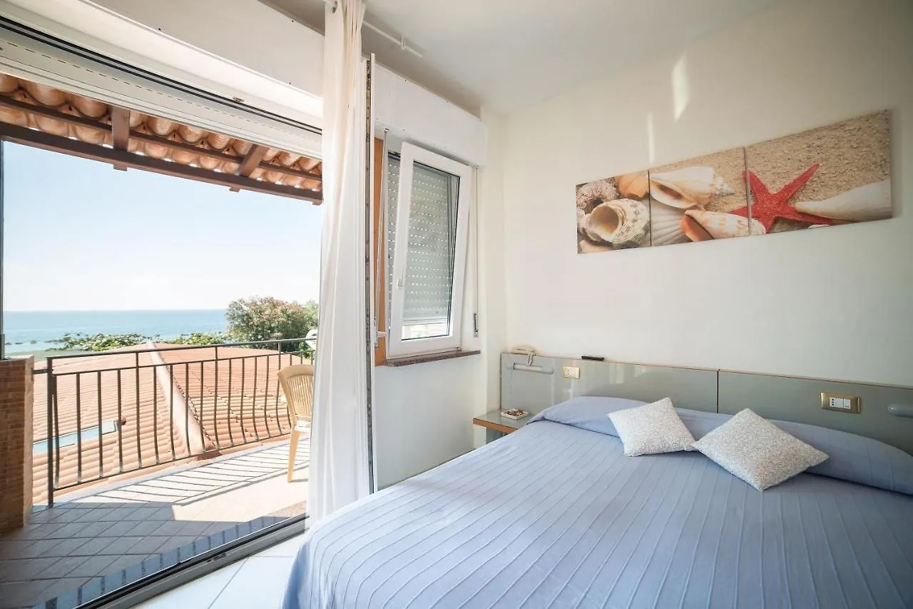 Camera matrimoniale luminosa con balcone e vista mare, letto azzurro e quadri di conchiglie