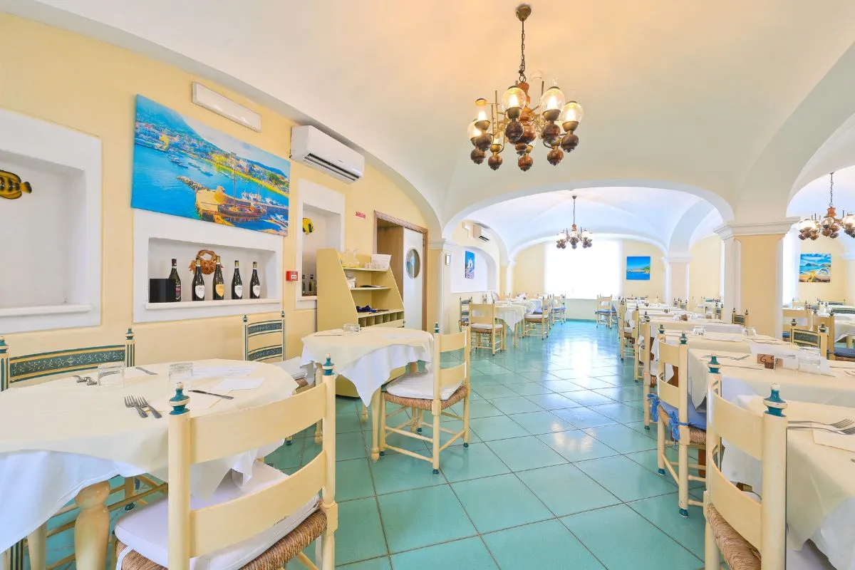 Sala ristorante con tavoli apparecchiati, pavimento verde e lampadari