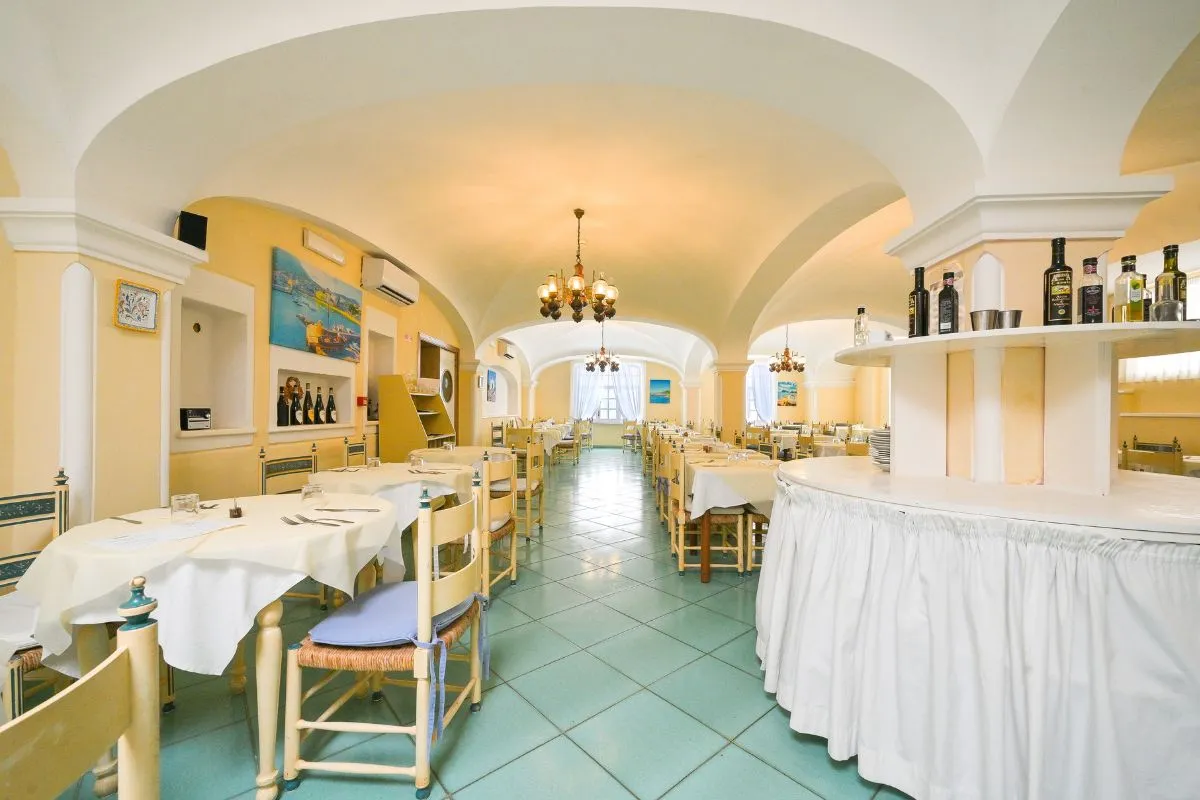 Sala ristorante con soffitto a volta, tavoli apparecchiati e bancone