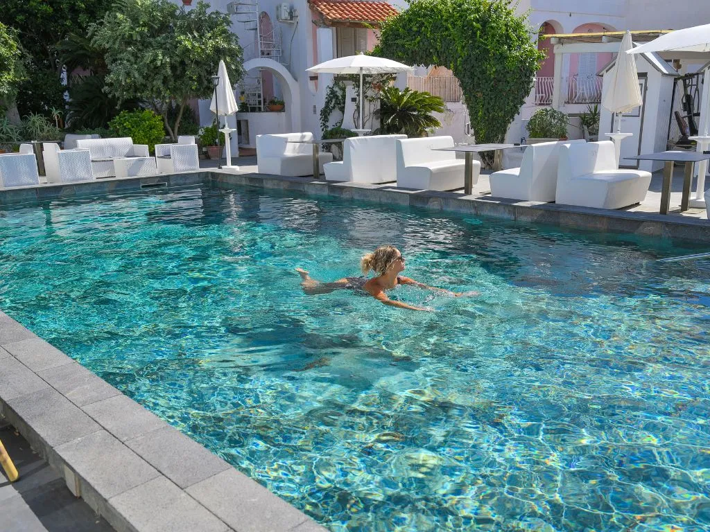 Piscina esterna con acqua cristallina e divanetti bianchi