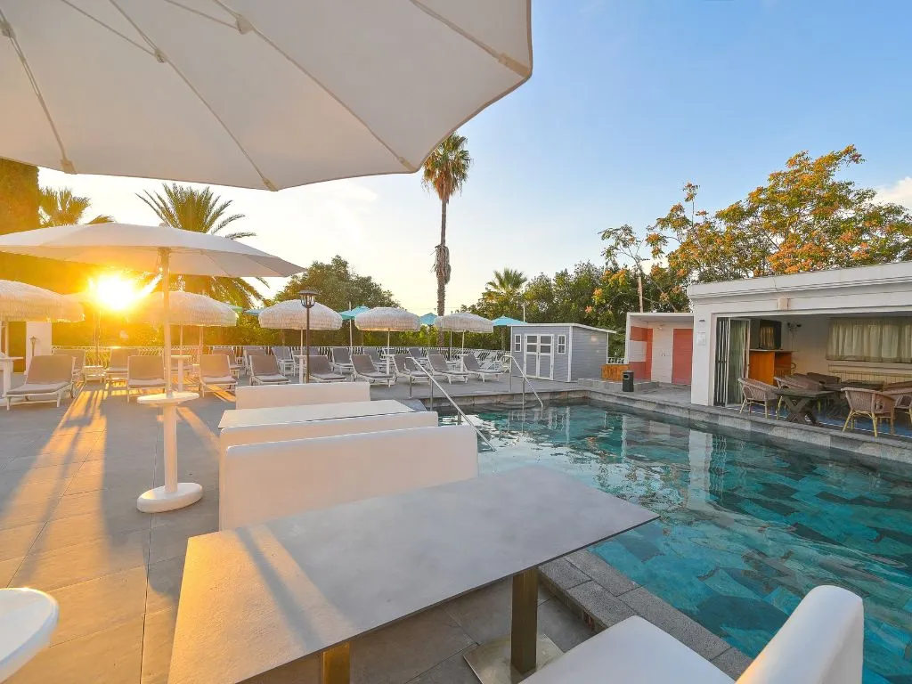 Piscina esterna al tramonto con lettini, ombrelloni e area lounge