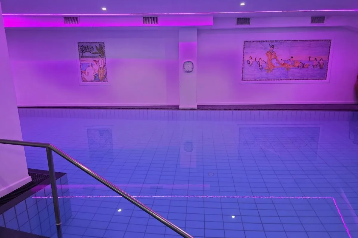 Piscina interna con illuminazione viola e affreschi decorativi alle pareti