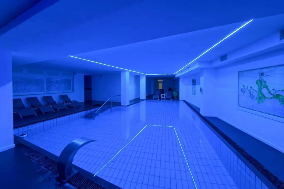 Piscina termale interna con luci blu al neon e opere d'arte alle pareti