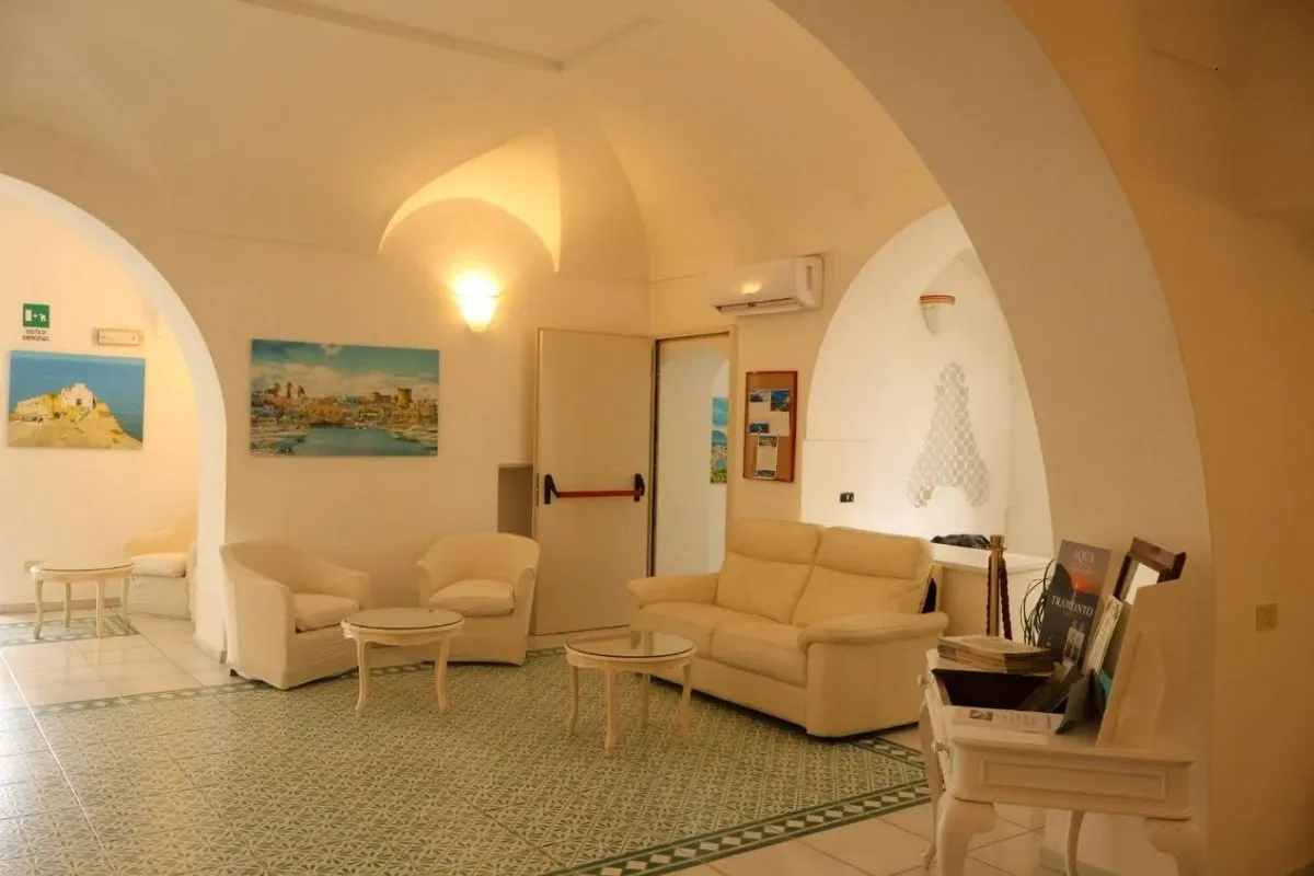 Salotto interno con divani, poltrone bianche e archi in stile mediterraneo