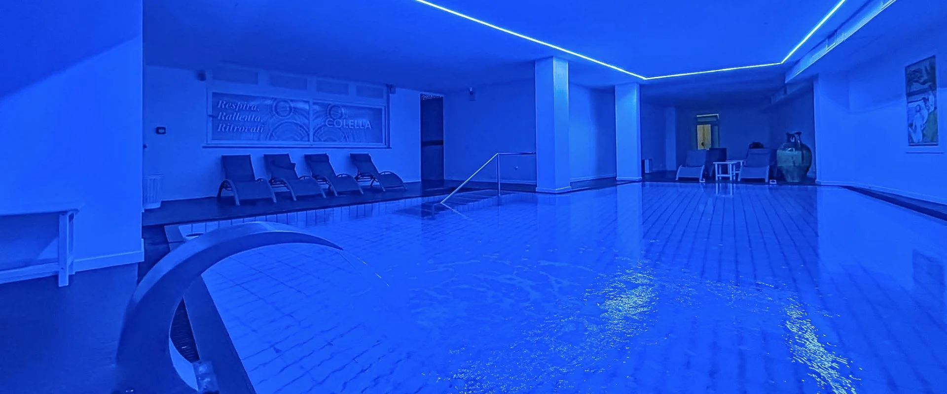 Piscina termale interna illuminata di blu con lettini relax