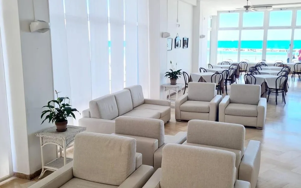 Sala soggiorno luminosa con divani bianchi e vista sul mare