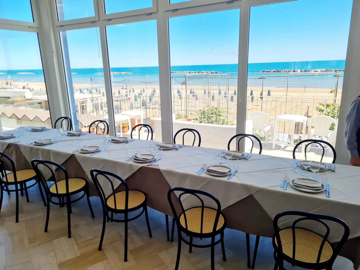 Sala ristorante con tavoli apparecchiati e vista panoramica sul mare