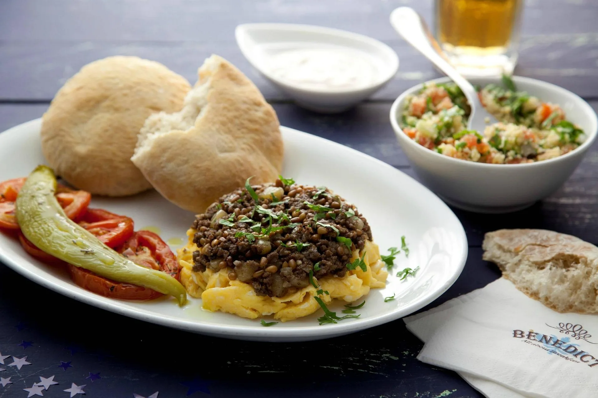 Piatto con uova strapazzate, carne, pomodori, pane pita e insalata