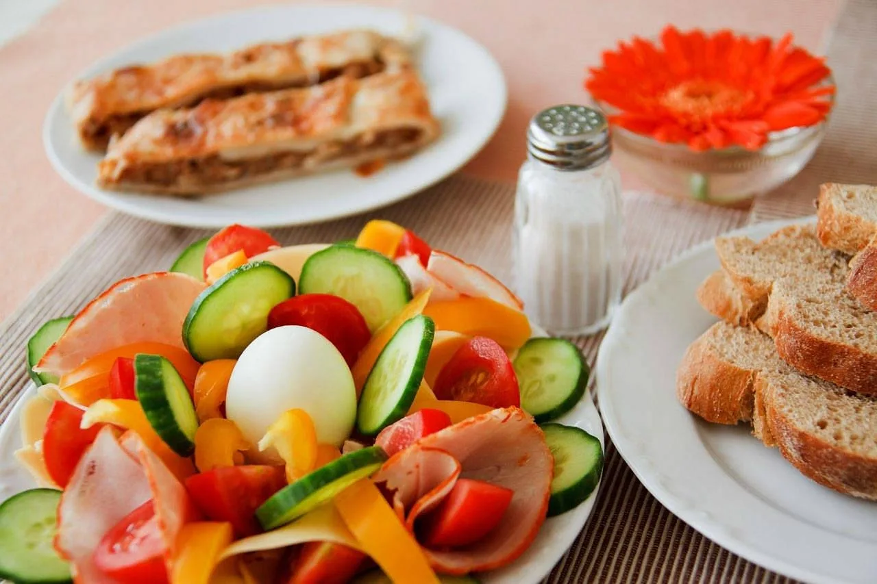 Piatto di insalata con affettati, verdure e uovo con pane e sfogliata