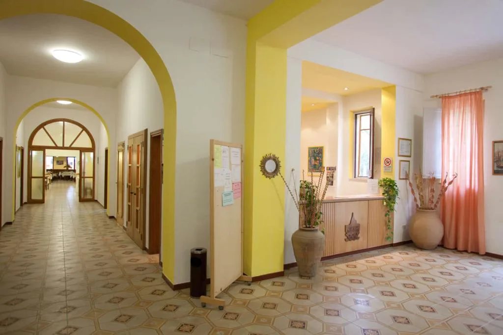 Corridoio con arco giallo, reception e grandi vasi decorativi