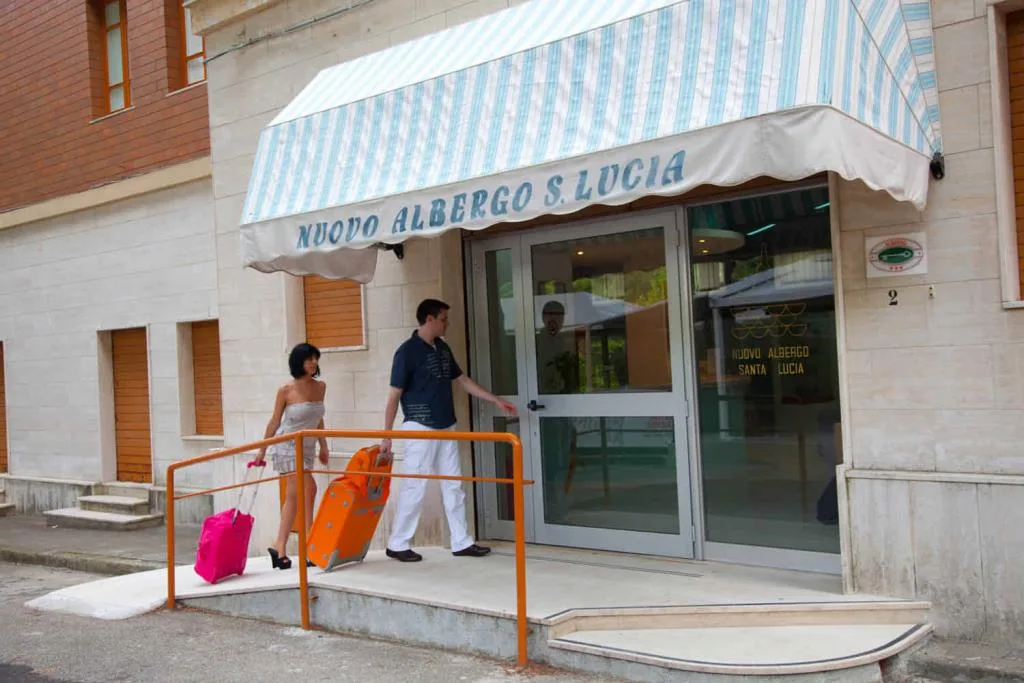 Ingresso esterno del Nuovo Albergo Santa Lucia con ospiti e valigie