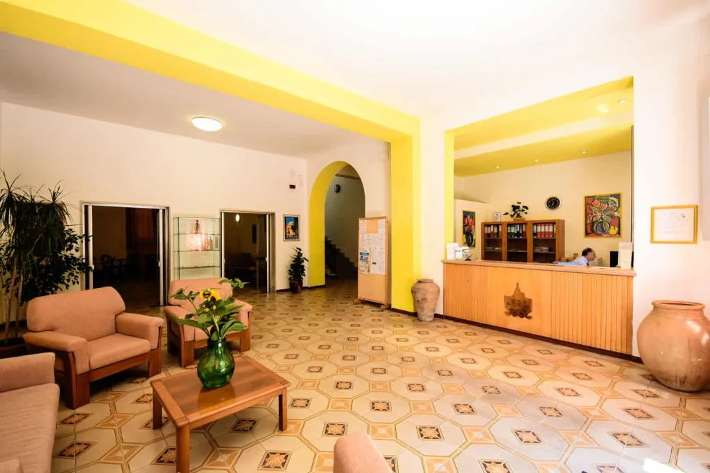 Reception in legno con parete gialla, divani e quadri decorativi