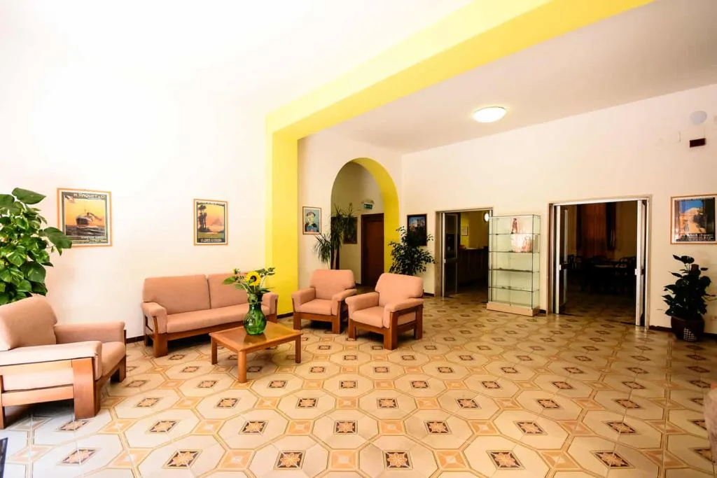 Sala comune con divani, poltrone beige e quadri alle pareti