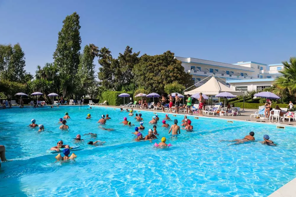 Ospiti in piscina durante attività di gruppo con hotel sullo sfondo