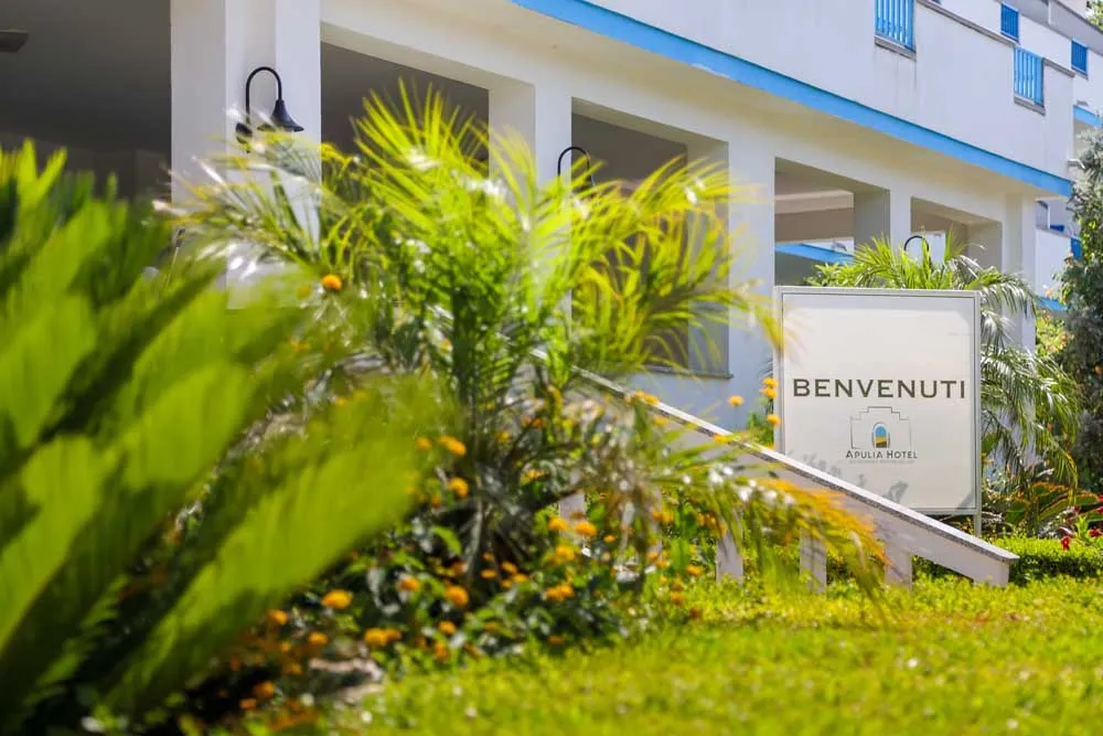 Insegna di benvenuto Apulia Hotel tra la vegetazione rigogliosa