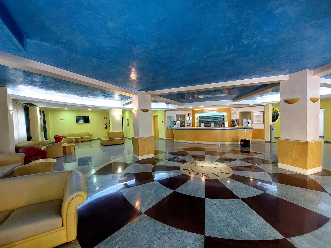 Hall dell'hotel con pavimento decorato, reception e zona salotto