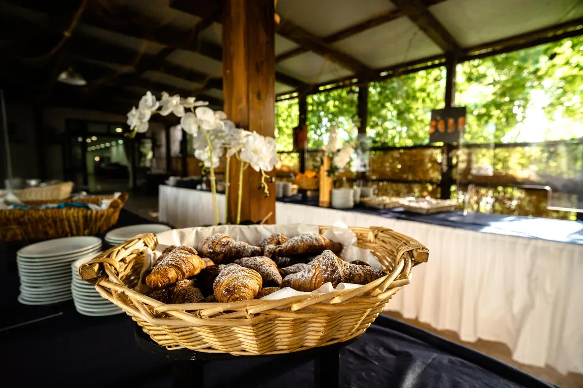 Cestino di cornetti freschi su buffet della colazione con orchidee