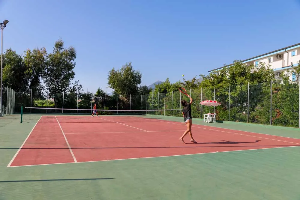 Persone giocano a tennis sul campo con vista sulle montagne