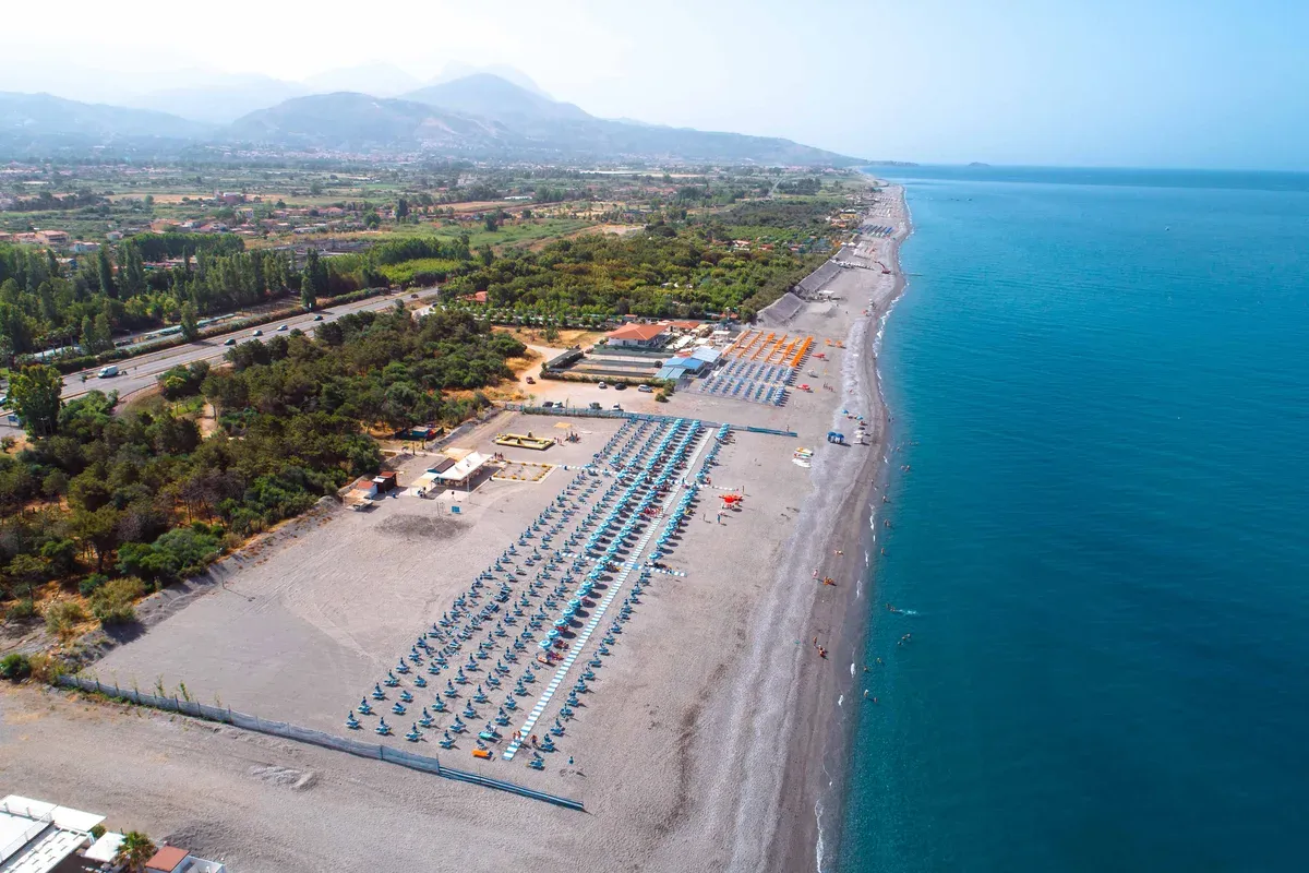 Veduta aerea della costa con spiaggia attrezzata, mare e montagne