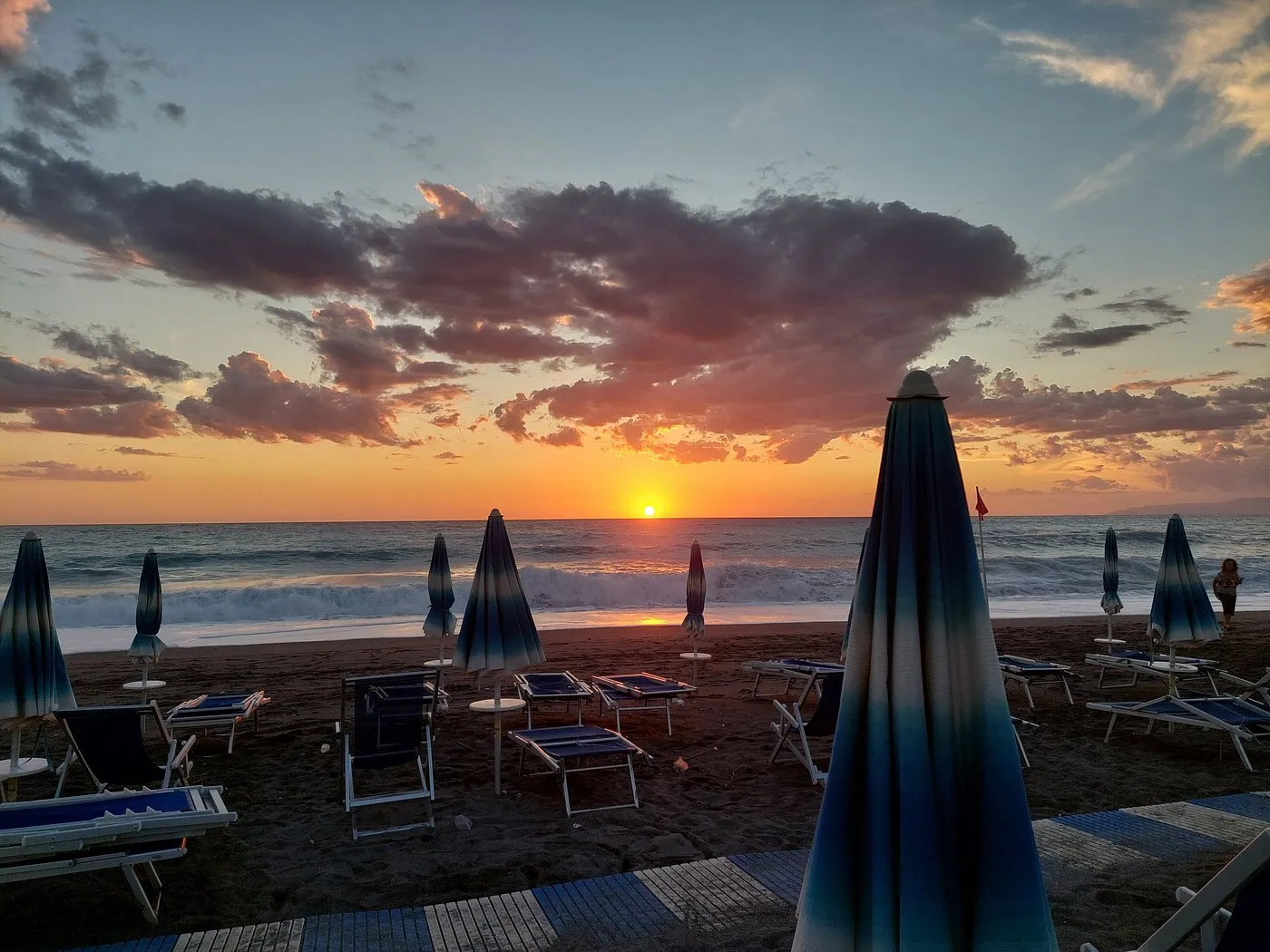 Tramonto sul mare con ombrelloni chiusi e lettini in spiaggia