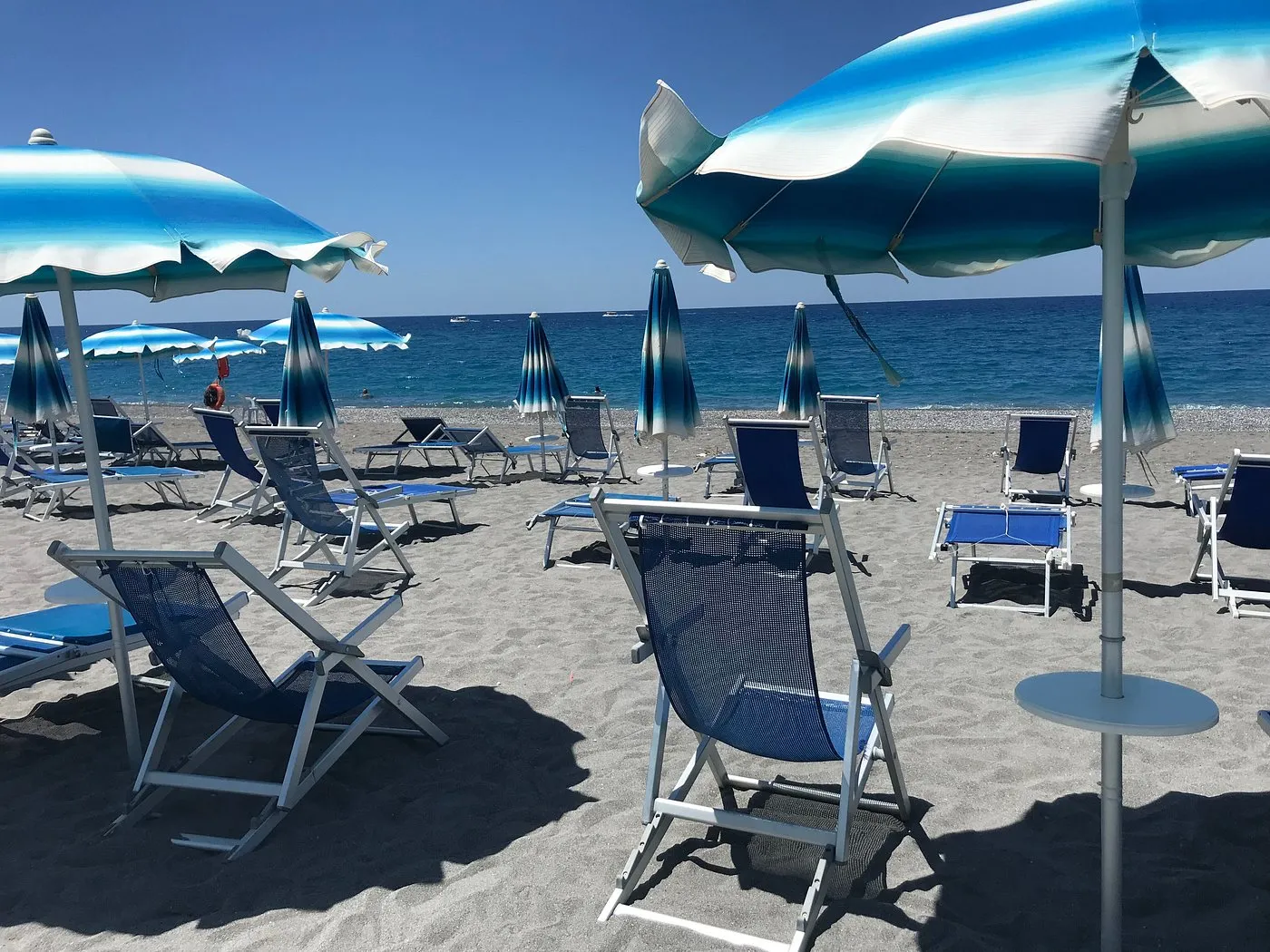 Spiaggia con ombrelloni azzurri e sdraio blu vista mare