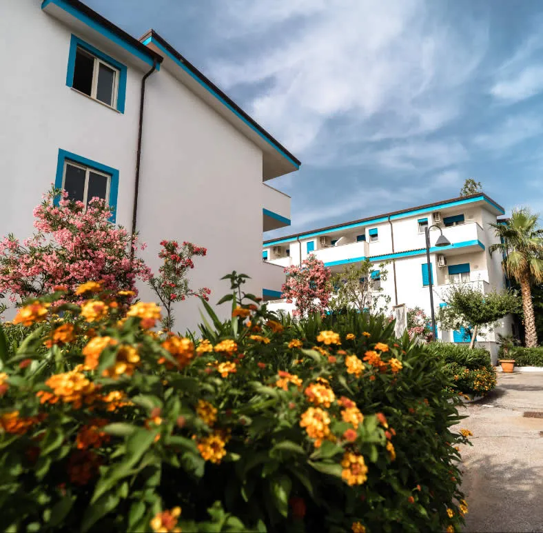 Esterno degli edifici dell'hotel con fiori colorati e palme