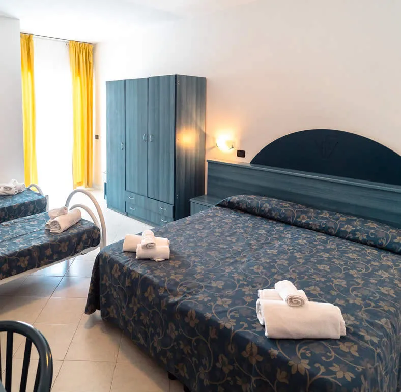 Camera tripla con letto matrimoniale e singolo, armadio e tende gialle