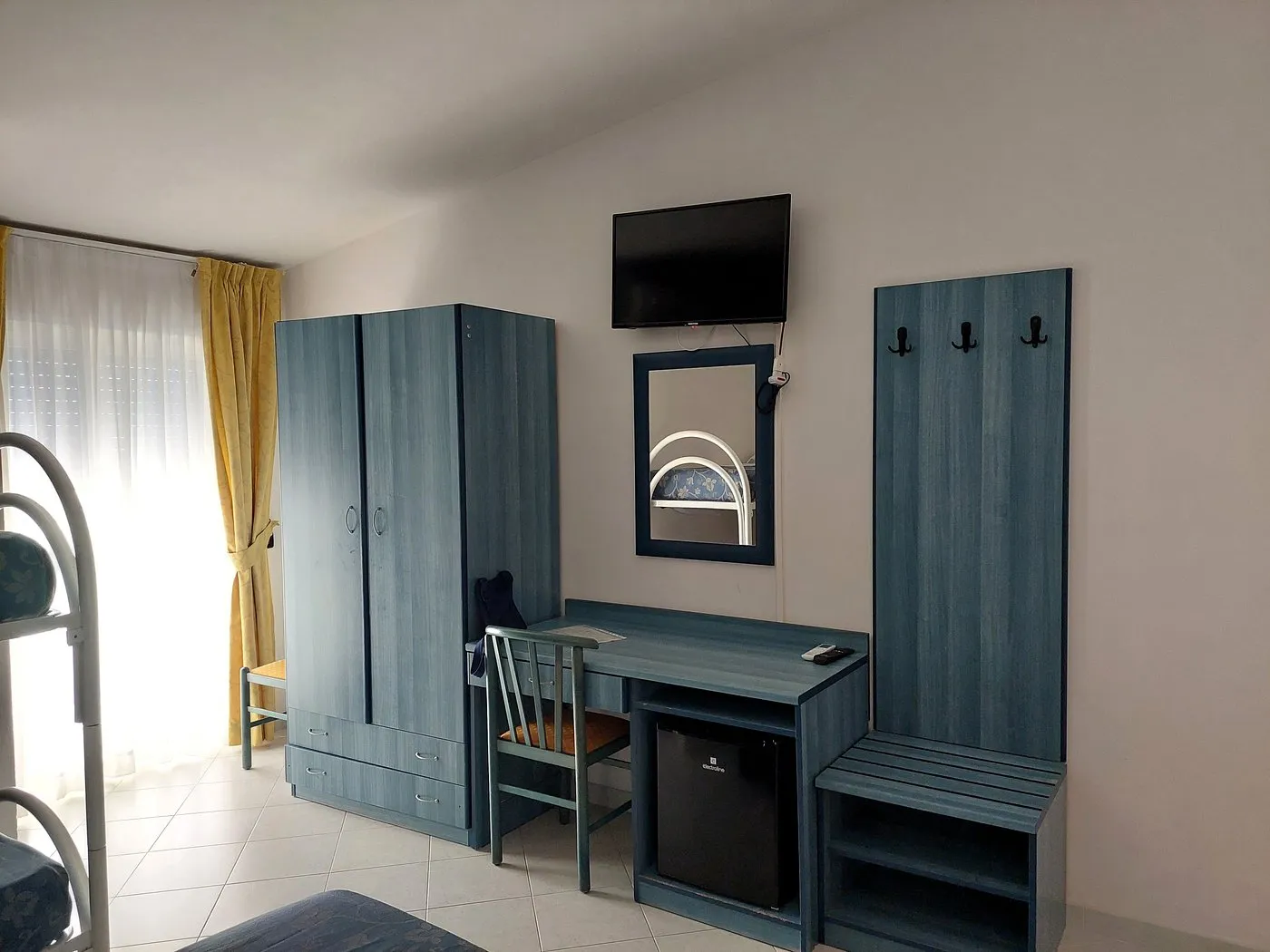 Dettaglio della camera con armadio, scrivania, TV e minibar