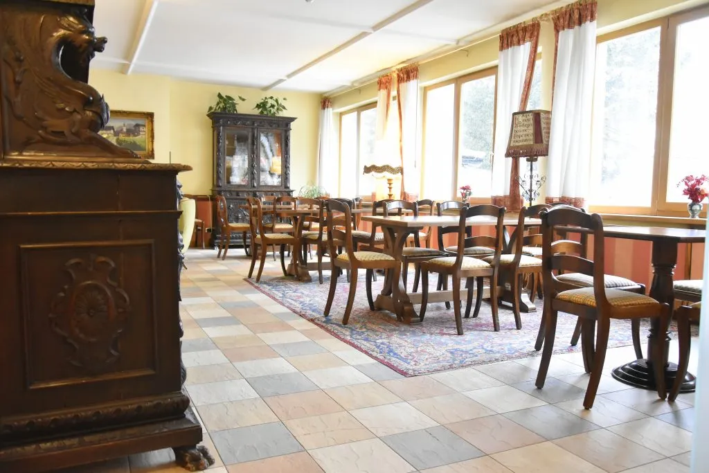 Sala luminosa con tavoli, sedie in legno e mobile intagliato antico vicino alle finestre