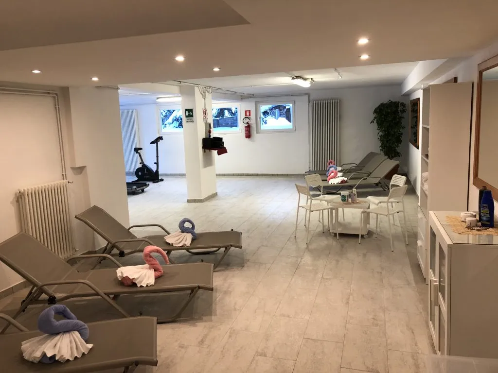 Zona relax della spa con lettini, area fitness con cyclette e asciugamani decorati
