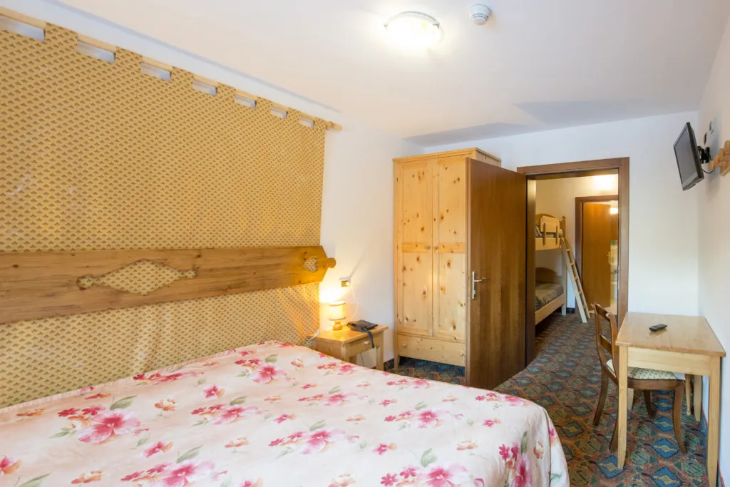 Camera matrimoniale con testiera in legno, armadio e collegamento a zona con letto a castello