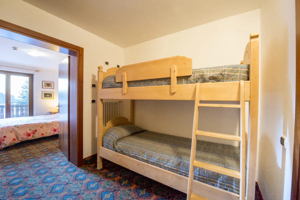 Camera con letto a castello in legno e vista sulla camera matrimoniale adiacente