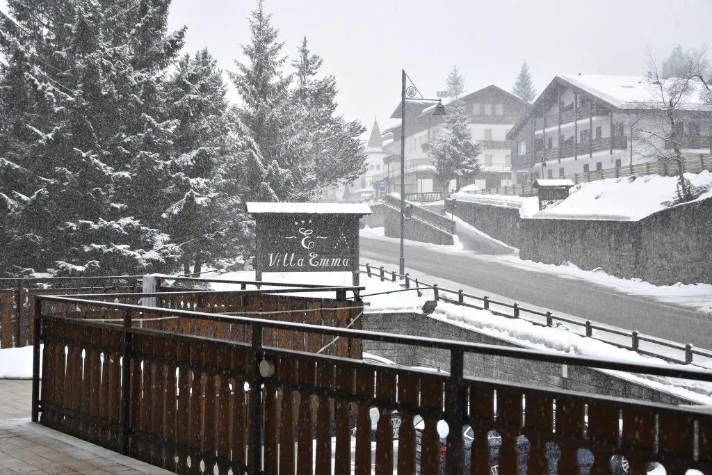 Vista invernale dalla terrazza dell'hotel con insegna Villa Emma, neve e abeti innevati
